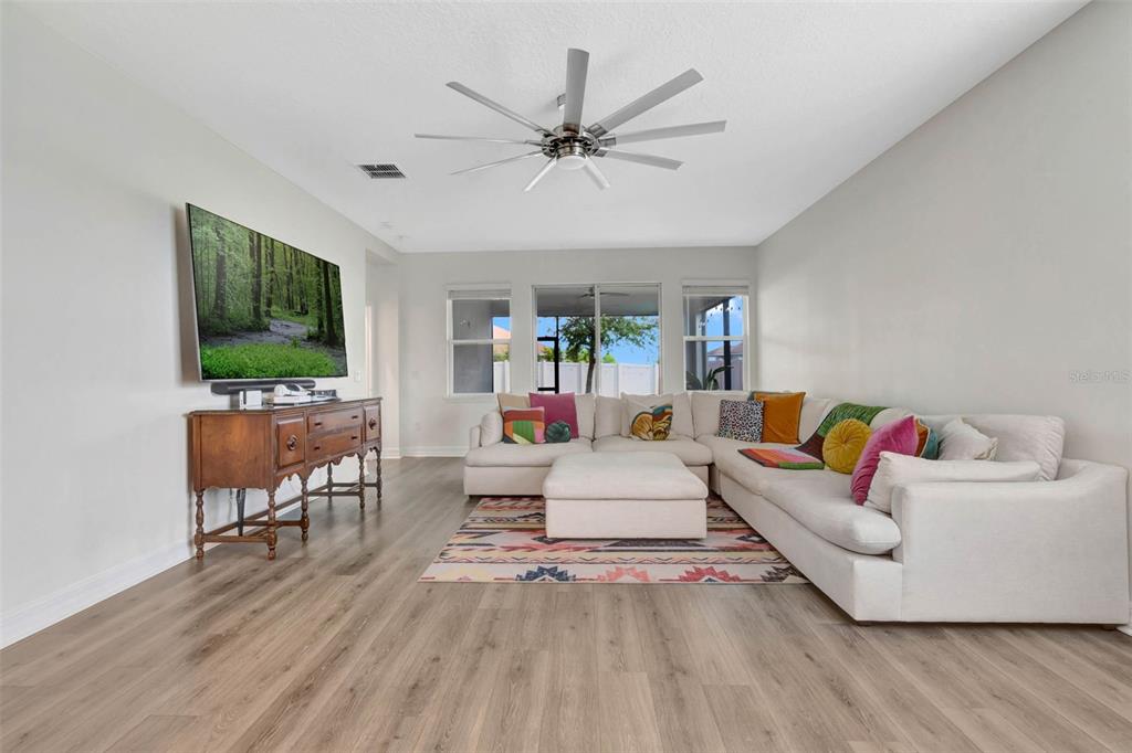 A living room features a large sectional sofa, a wooden console, and a ceiling fan — 3112 AMBERSWEET PLACE, CLERMONT, FL