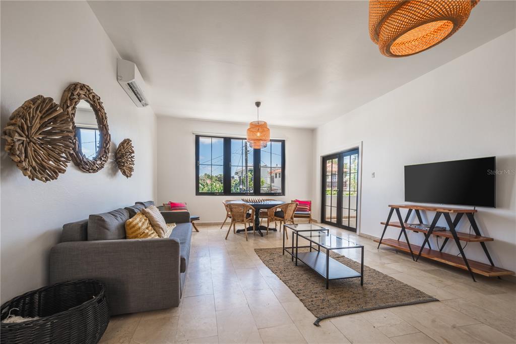 A living room features a gray sofa, a dining area, and a wall-mounted television — 2008 CACIQUE, SAN JUAN, PR