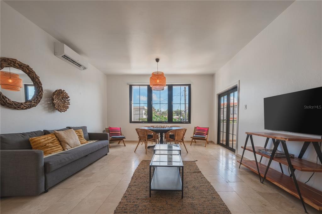 A living and dining area features tile floors, a gray sofa, and a central window — 2008 CACIQUE, SAN JUAN, PR