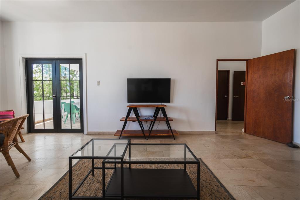 A living room features a glass coffee table, a television on a wooden stand, and tile flooring — 2008 CACIQUE, SAN JUAN, PR