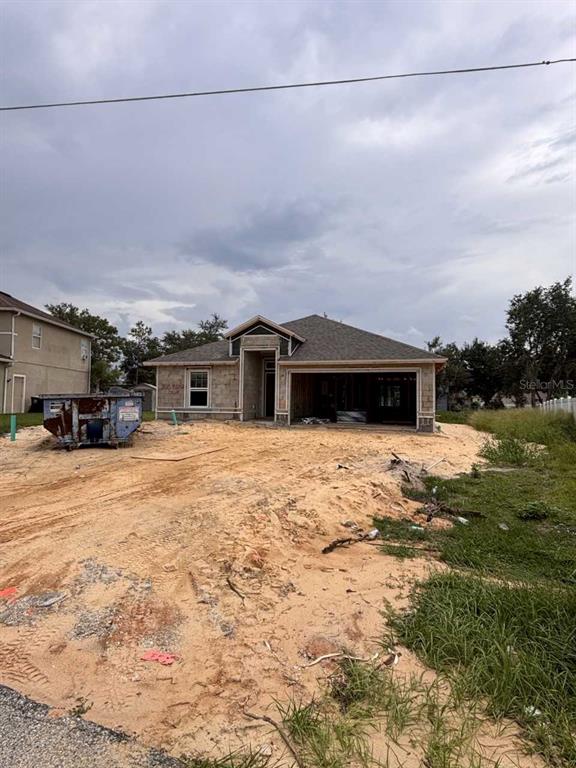 A single-story house under construction with an open garage and sandy front yard — 1925 MICHIGAN DRIVE, POINCIANA, FL