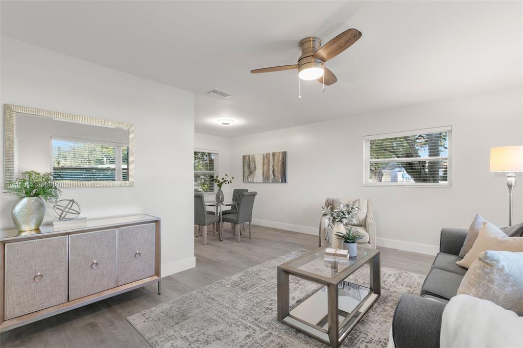 A living room and dining area with light wood flooring, a ceiling fan, and furniture — 5931 DENVER STREET NE, ST PETERSBURG, FL