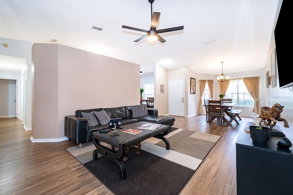 A living room with a black sectional sofa, coffee table, and wood-look flooring — 25741 BELLE HELENE, LEESBURG, FL