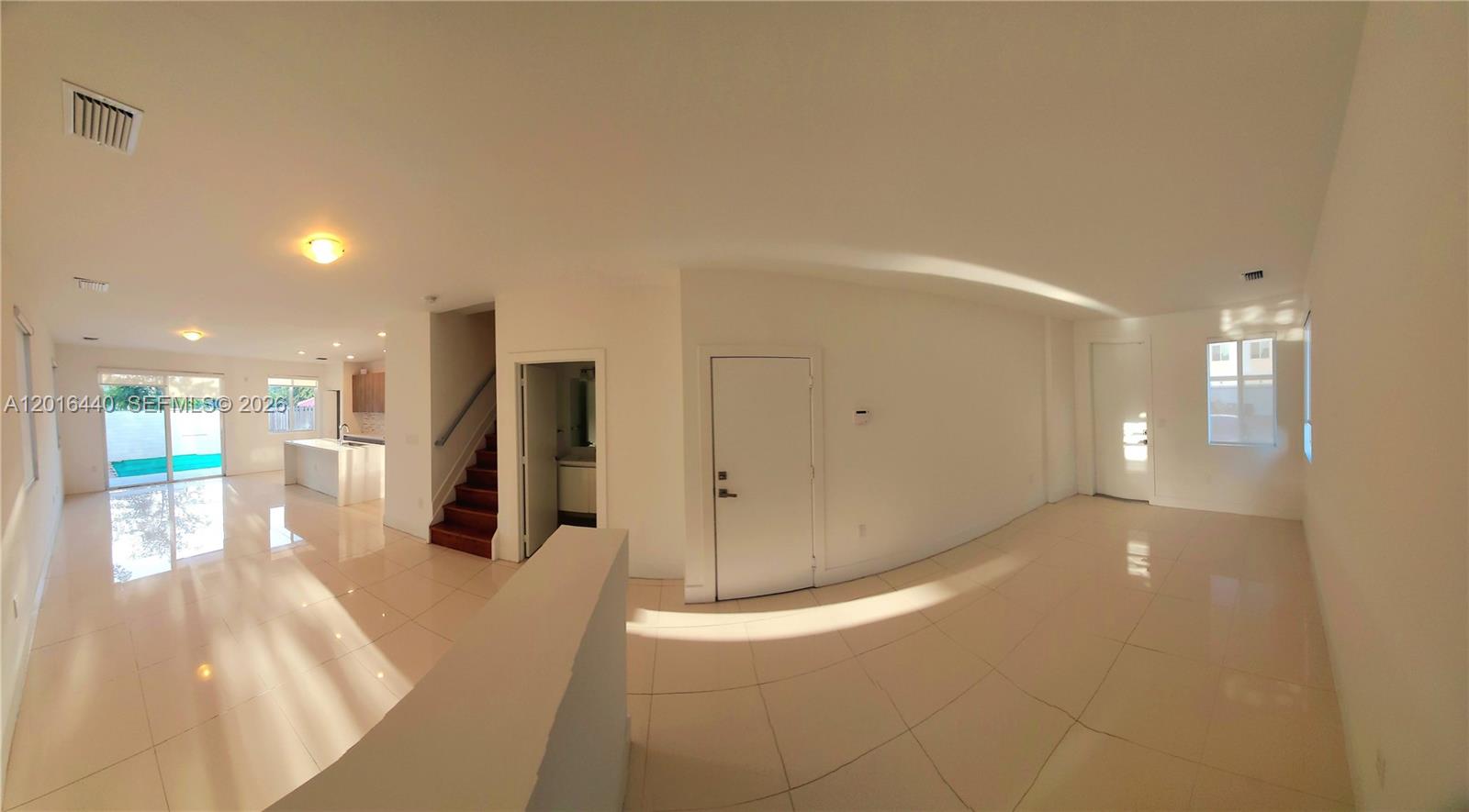 An open-concept living area features white tile floors, a staircase, and a kitchen — 7210 NW 103rd Path, Doral FL 33178, DORAL, FL