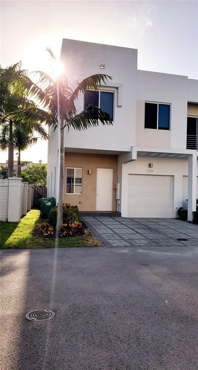 A two-story townhouse exterior features a white facade, a single-car garage, and a palm tree — 7210 NW 103rd Path, Doral FL 33178, DORAL, FL