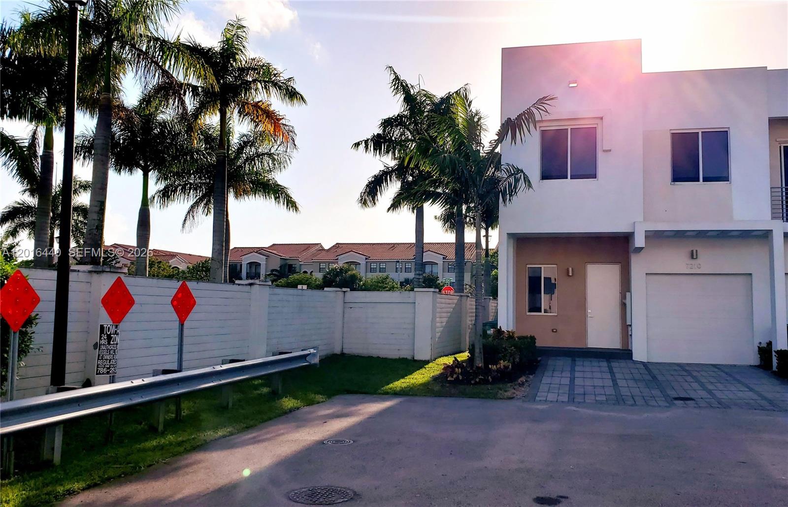 A two-story residential building with a white facade, a garage, and palm trees in front — 7210 NW 103rd Path, Doral FL 33178, DORAL, FL