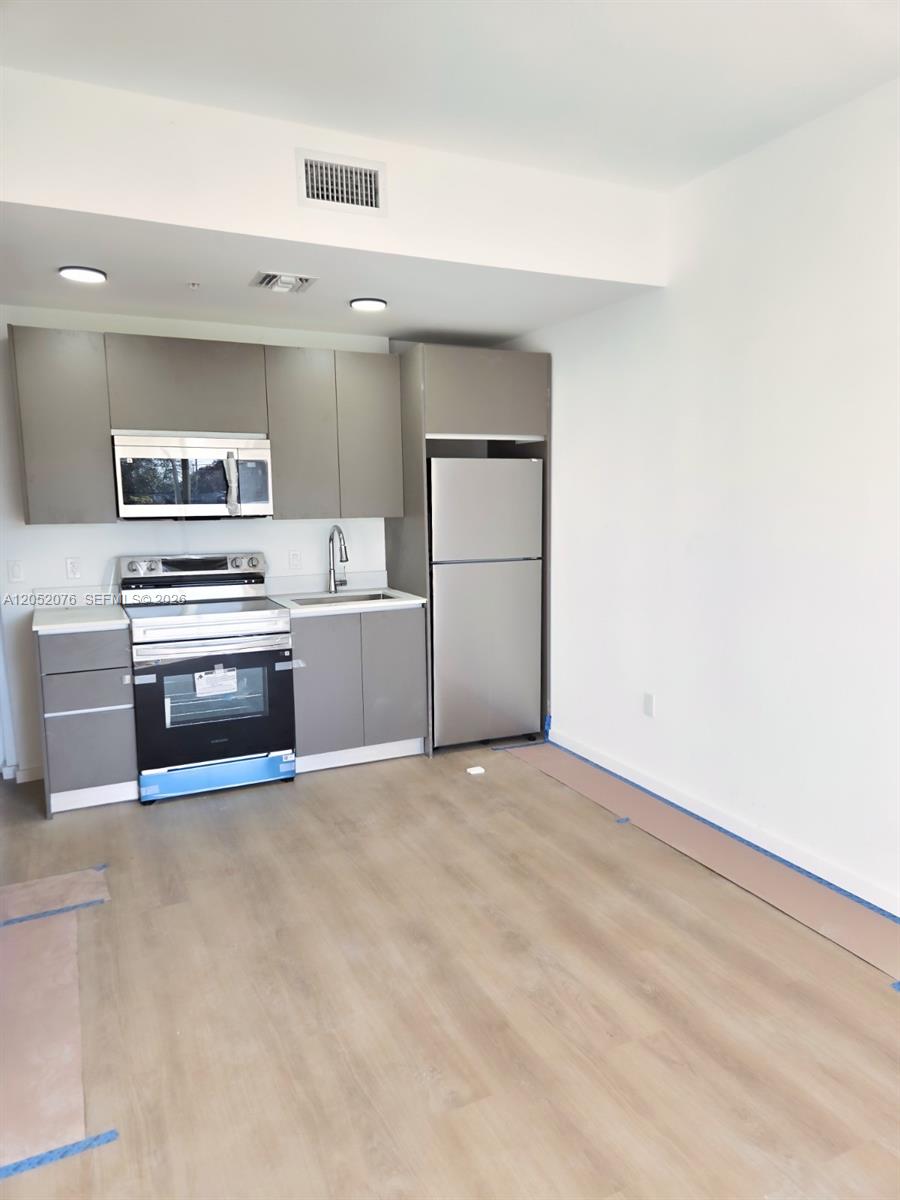 A kitchen features gray cabinets, stainless steel appliances, and light wood-look flooring — 8106 NE 1st Ave # 8, Miami FL 33138, MIAMI, FL