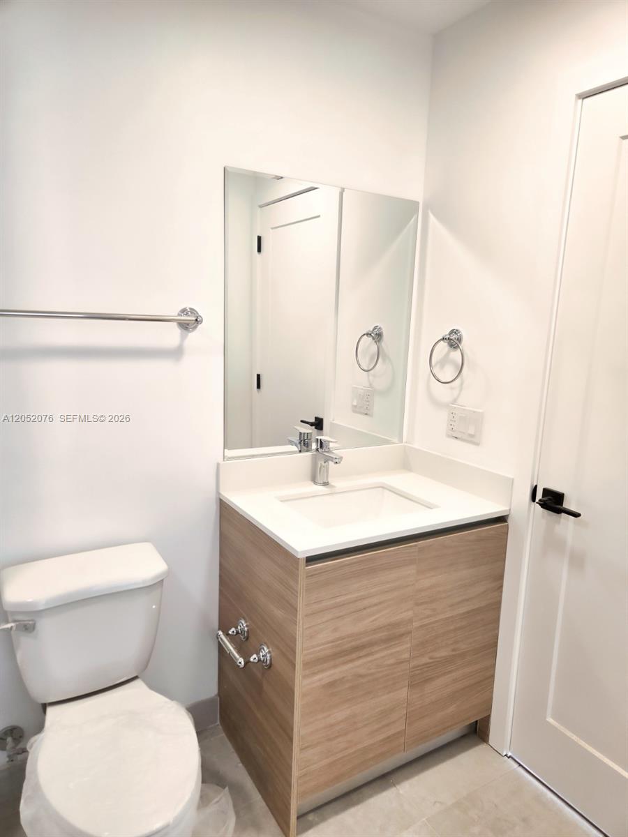 A modern bathroom features a wood-grain vanity, white countertop, and a wall-mounted mirror — 8106 NE 1st Ave # 8, Miami FL 33138, MIAMI, FL