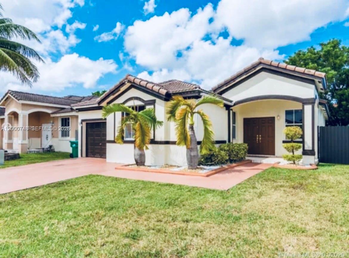 A single-story house with a tan exterior, dark trim, a garage, and two palm trees — 8135 NW 198th Ter, Hialeah FL 33015, HIALEAH, FL