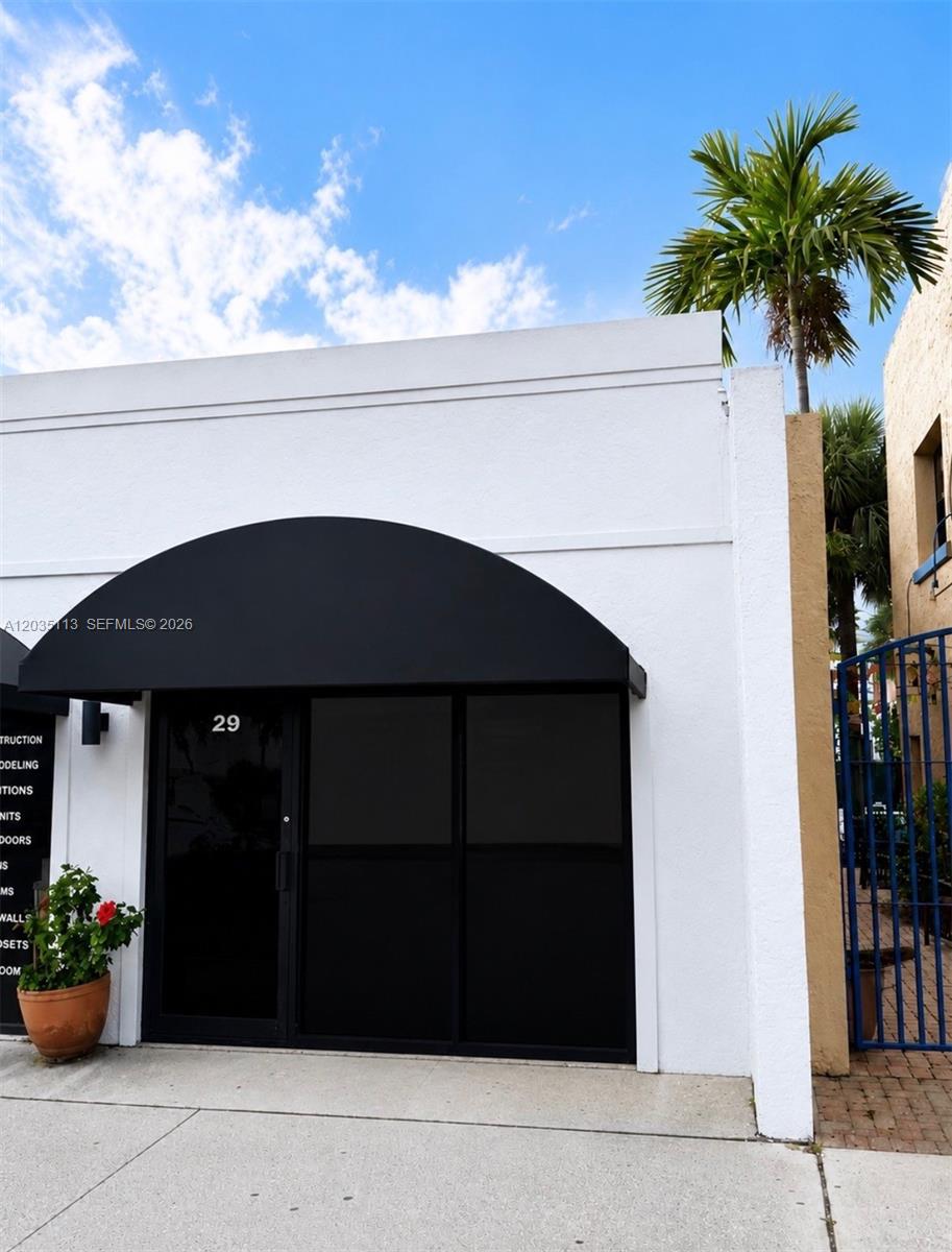 A white building exterior features a black arched awning over a dark glass entrance door — 29 S J St, FL 33460, FL