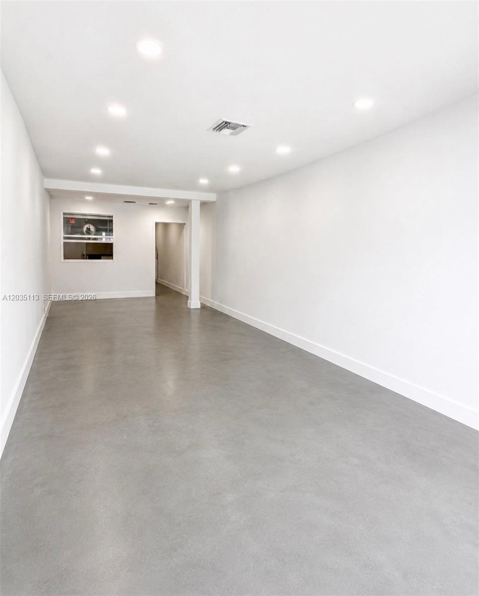 An empty, minimalist room features white walls, recessed ceiling lights, and a smooth gray floor — 29 S J St, FL 33460, FL