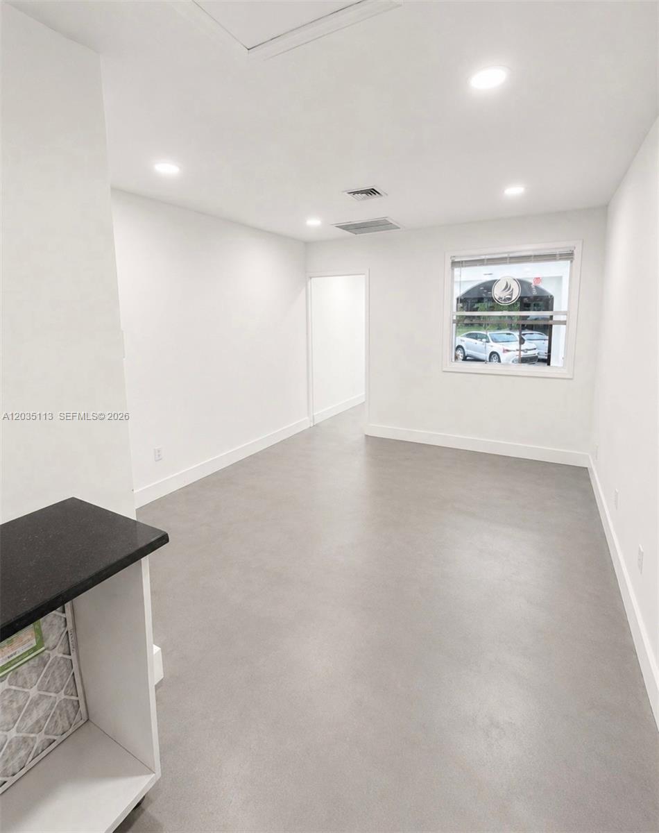 A minimalist room features white walls, gray flooring, recessed lighting, and a window overlooking cars — 29 S J St, FL 33460, FL