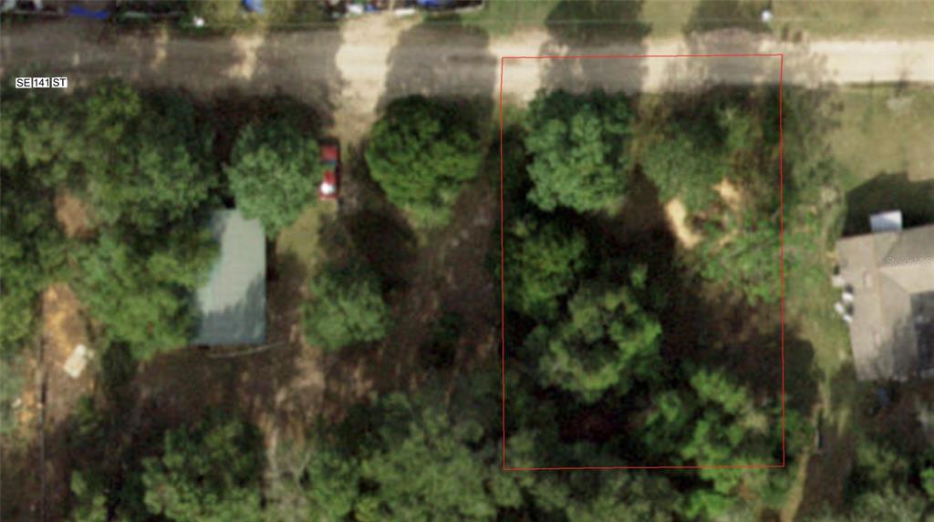 An aerial view shows a rectangular, tree-covered vacant lot outlined in red next to a house — 20180 SE 141ST STREET, UMATILLA, FL