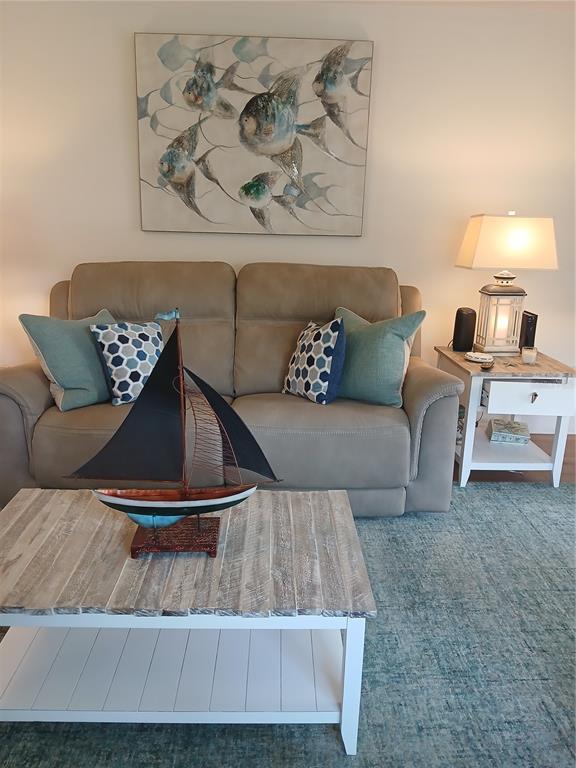 A living room features a tan loveseat, a wooden coffee table with a sailboat model, and coastal decor — 200 GLENNES LANE UNIT 103, DUNEDIN, FL
