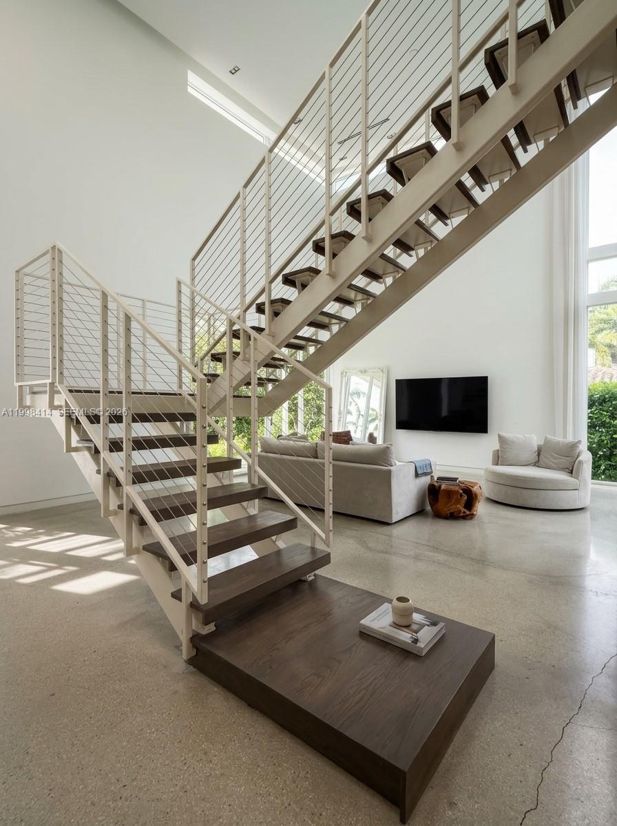 A modern living room features a prominent floating staircase with dark wood treads and railings — 949 Tyler St, Hollywood FL 33019, HOLLYWOOD, FL