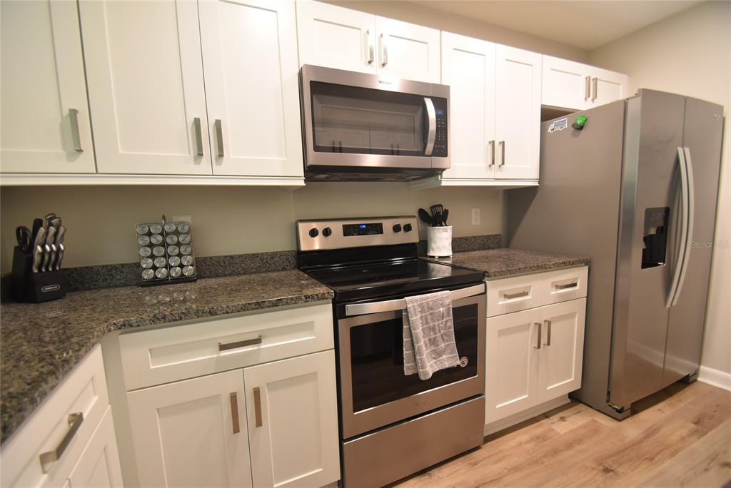 A kitchen features white cabinets, stainless steel appliances, and dark granite countertops — 1720 GLENHOUSE DRIVE UNIT GL427, SARASOTA, FL