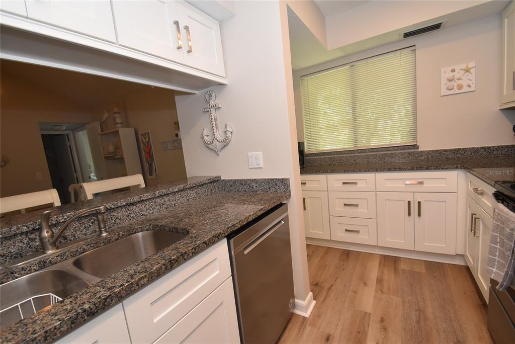 A kitchen with white cabinets, granite countertops, stainless steel appliances, and wood-look flooring — 1720 GLENHOUSE DRIVE UNIT GL427, SARASOTA, FL