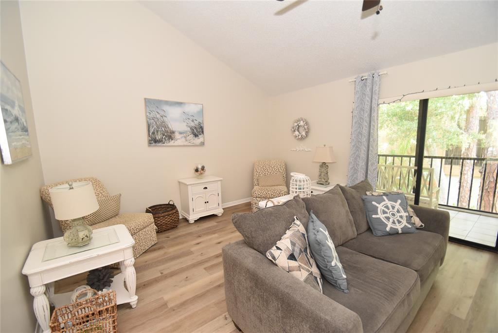 A living room features light wood-look flooring, a gray sofa, and a sliding glass door — 1720 GLENHOUSE DRIVE UNIT GL427, SARASOTA, FL
