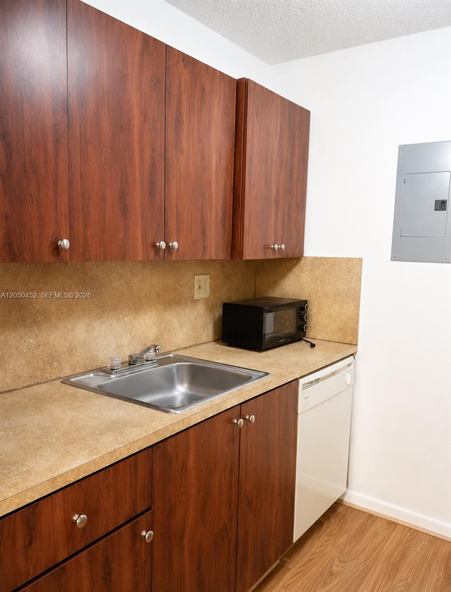 A kitchen features wood-grain cabinets, a stainless steel sink, and a white dishwasher — 7407 SW 152nd Ave # 204, Miami FL 33193, MIAMI, FL