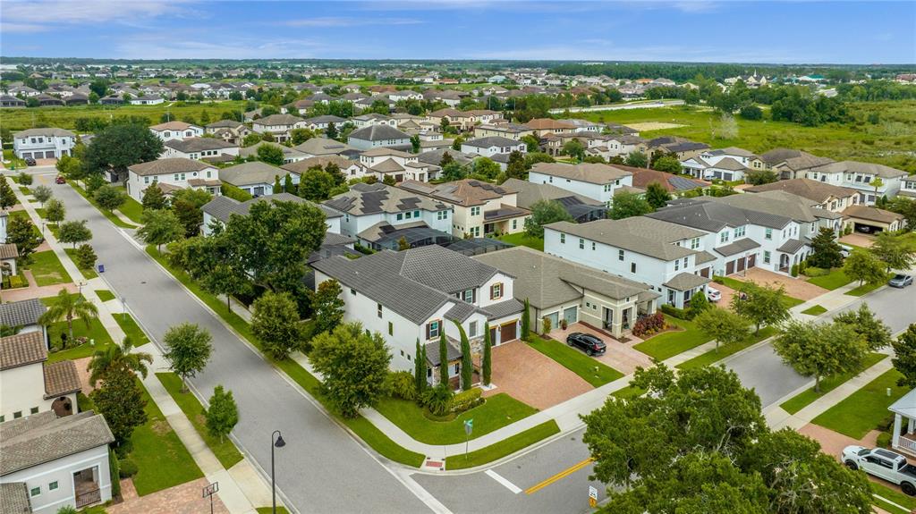 An aerial view shows a suburban neighborhood with houses, paved streets, and green lawns — 1734 AMSEL FALLS PARK TERRACE, WINTER GARDEN, FL
