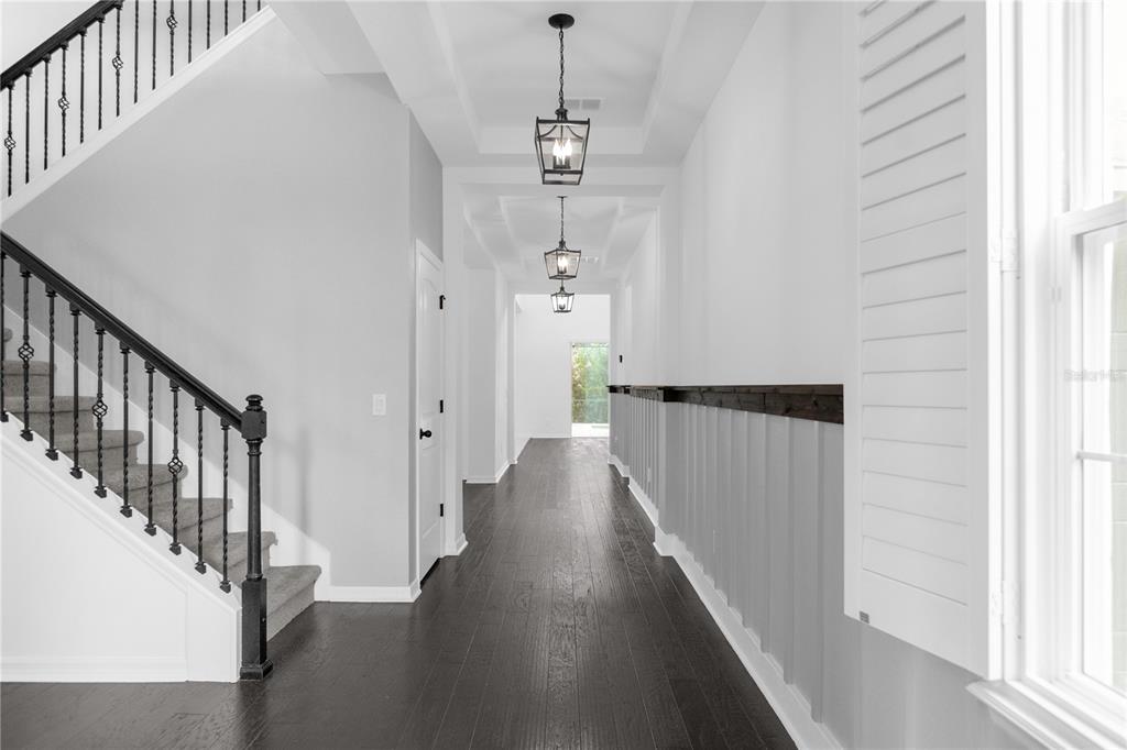 A long hallway features dark wood floors, a staircase, and a gallery wall with framed art — 1734 AMSEL FALLS PARK TERRACE, WINTER GARDEN, FL