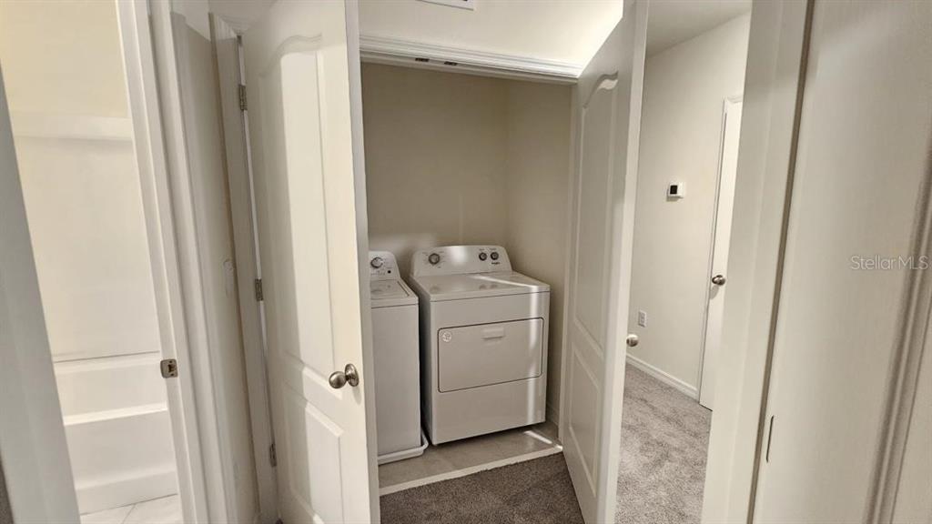 A laundry closet with a washer and dryer sits between two doorways in a hallway — 1975 TAMARACK PASS, DAVENPORT, FL