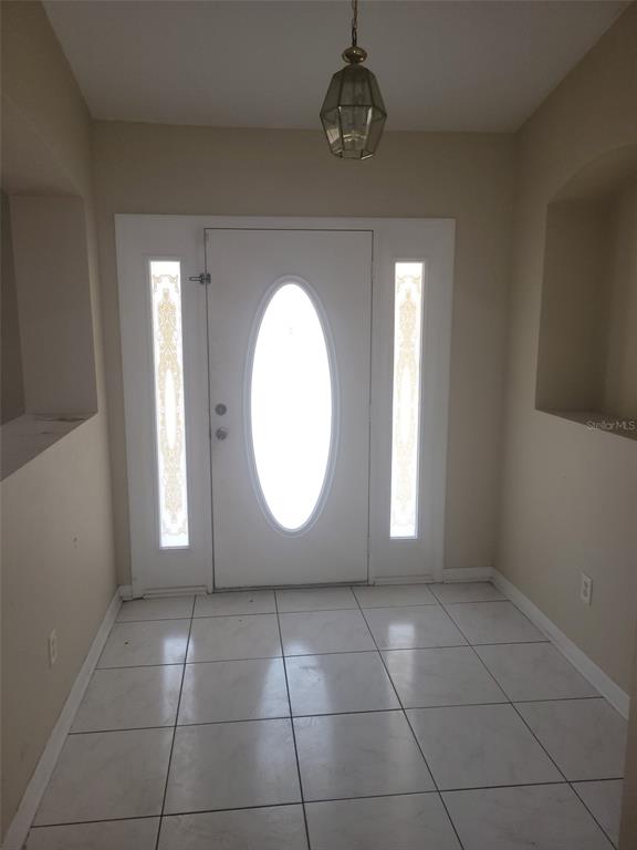 A tiled entryway features a white front door with an oval window and sidelights — 4650 NE 16TH PLACE, OCALA, FL