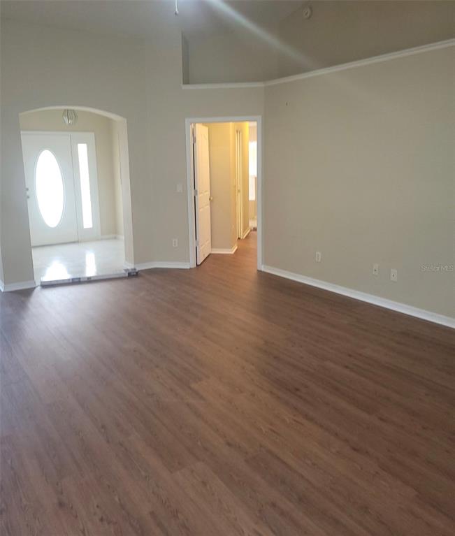 An interior view shows a room with wood-look flooring, beige walls, and an arched entryway — 4650 NE 16TH PLACE, OCALA, FL