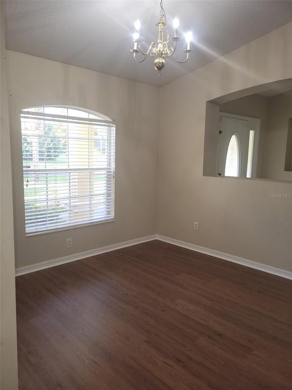 An empty dining room features wood-look flooring, a chandelier, and a large arched window — 4650 NE 16TH PLACE, OCALA, FL