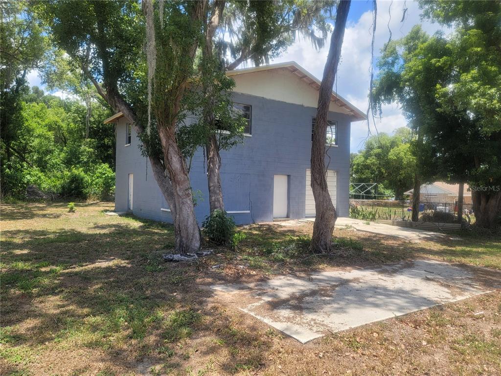 A two-story blue concrete block building stands on a grassy lot with mature trees — 510C TIGHE STREET, SEFFNER, FL