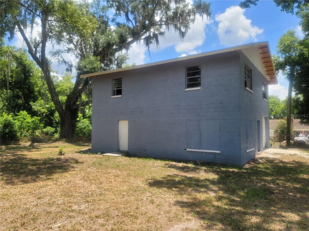 A two-story gray concrete block building stands on a grassy lot with mature trees — 510C TIGHE STREET, SEFFNER, FL