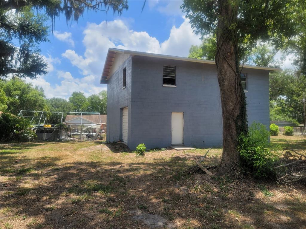 A two-story gray concrete block building stands in a grassy yard with a large tree — 510C TIGHE STREET, SEFFNER, FL