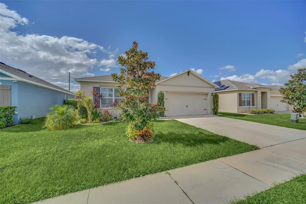 A single-story suburban house with a beige exterior, a two-car garage, and a landscaped lawn — 3308 COUNTRY WALK CLUB CIRCLE, WINTER HAVEN, FL
