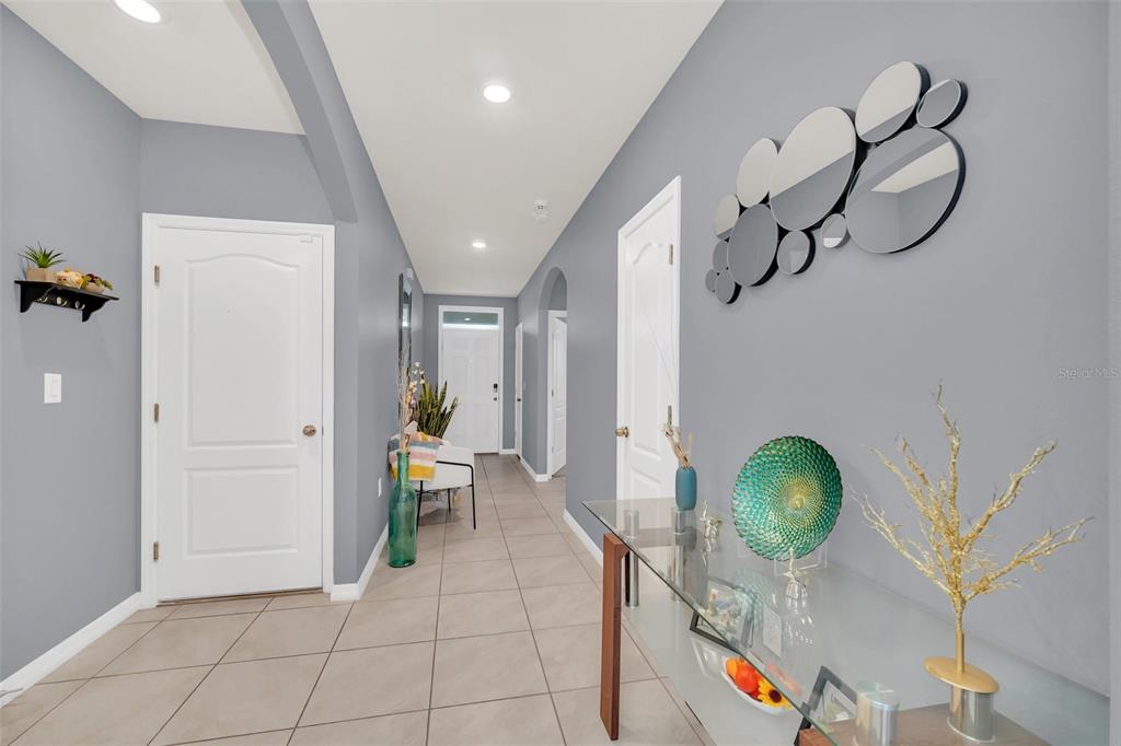 A hallway with gray walls, tile flooring, white doors, and a glass console table — 3308 COUNTRY WALK CLUB CIRCLE, WINTER HAVEN, FL