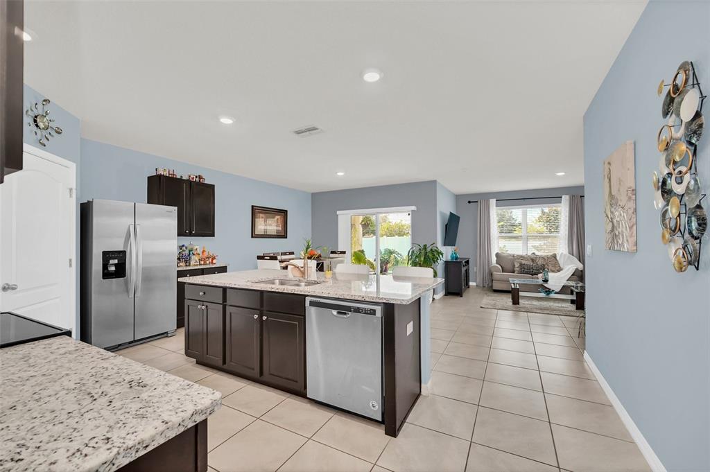 A kitchen with dark cabinets and granite countertops opens into a living area with tile — 3308 COUNTRY WALK CLUB CIRCLE, WINTER HAVEN, FL
