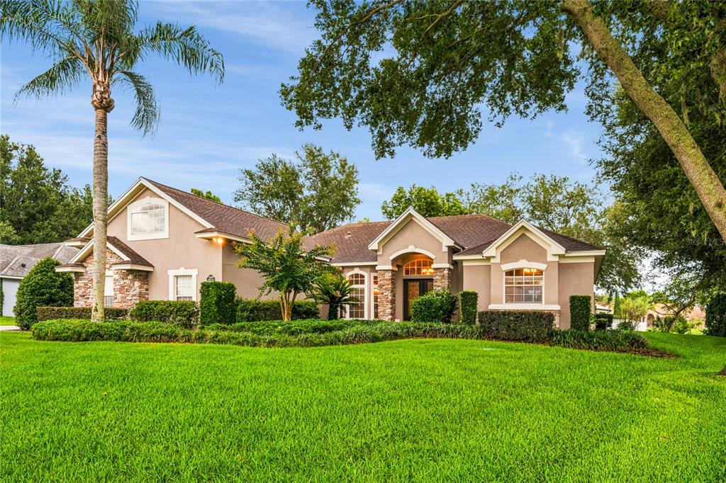 A single-story suburban house with a tan stucco exterior, stone accents, and a large lawn — 12426 LAKE VIEW LANE, CLERMONT, FL