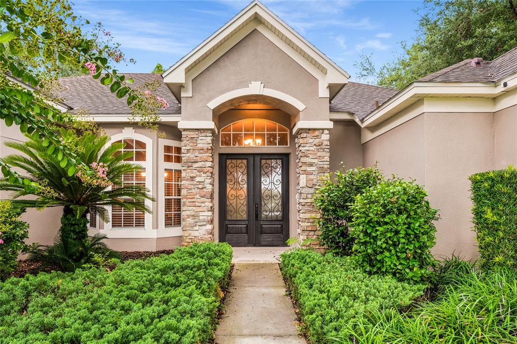 The exterior of a house features a stone-accented entryway with double doors and landscaping — 12426 LAKE VIEW LANE, CLERMONT, FL