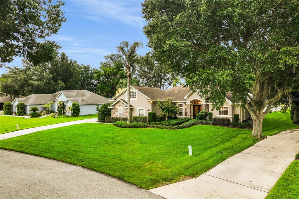 A single-story house with a tan exterior, stone accents, and a large front lawn — 12426 LAKE VIEW LANE, CLERMONT, FL
