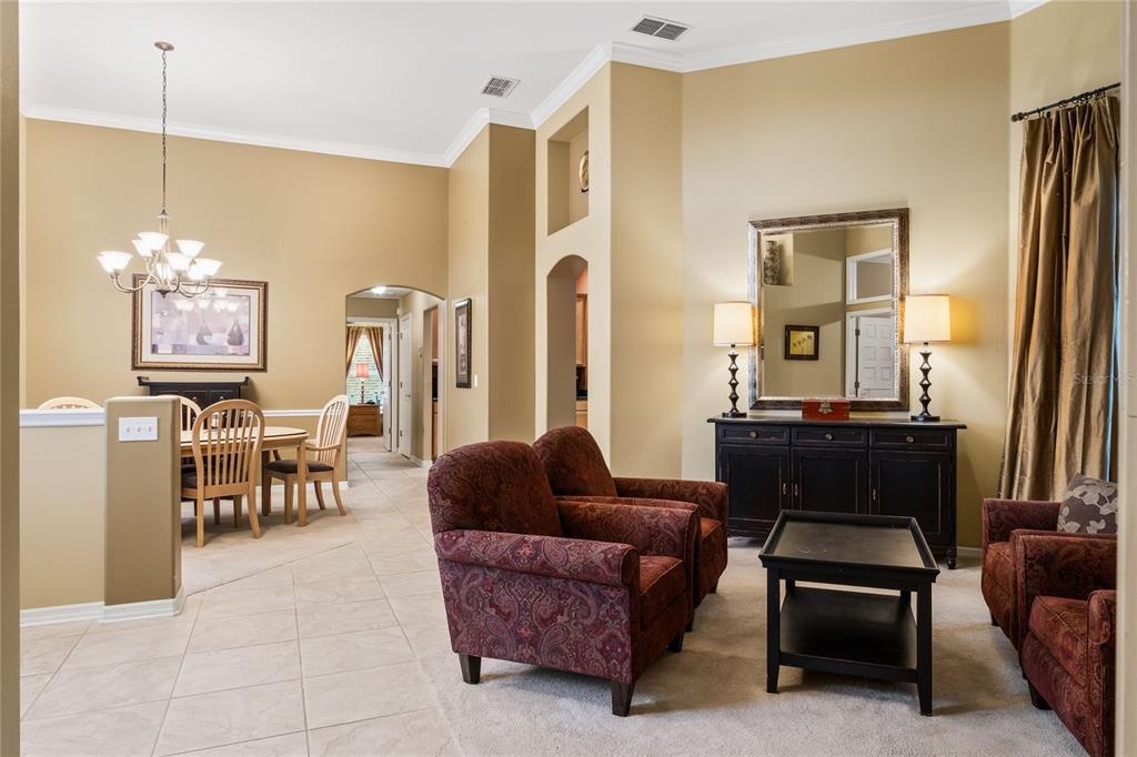 A living room with red patterned armchairs and a dining area with a chandelier — 12426 LAKE VIEW LANE, CLERMONT, FL