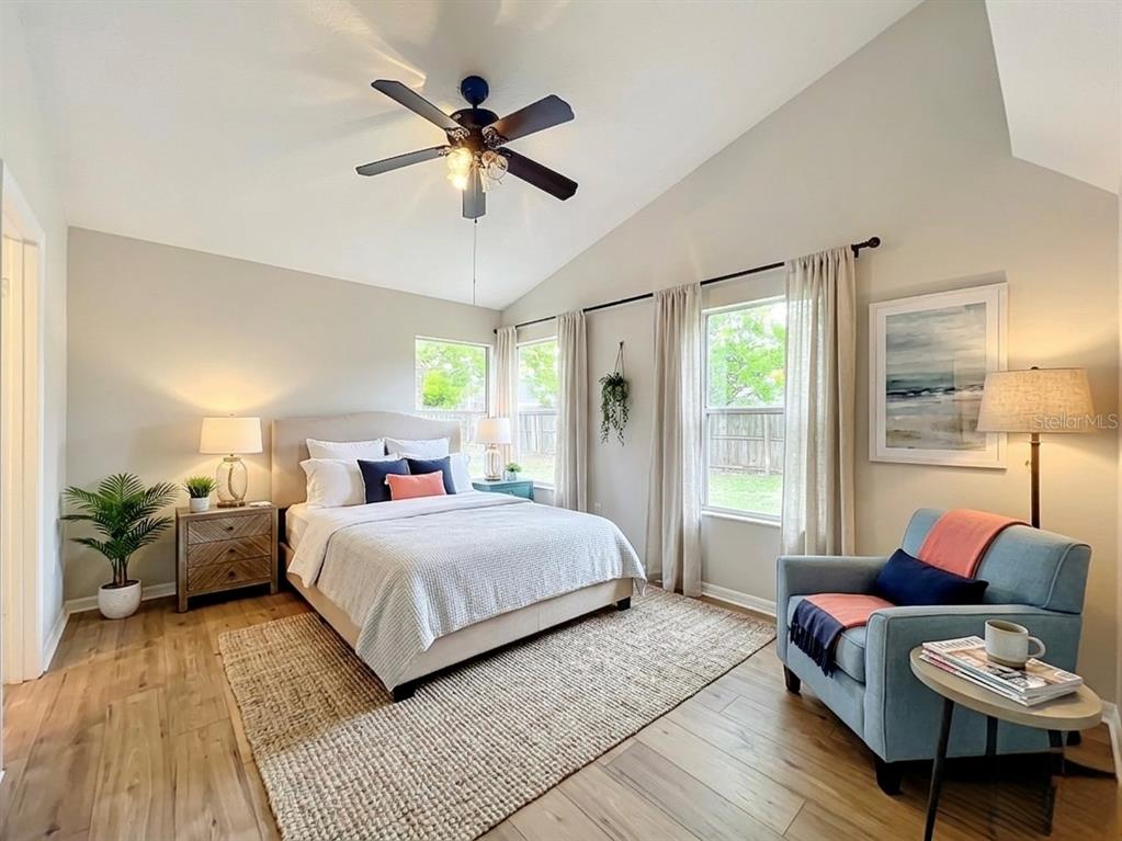 An empty room features a vaulted ceiling, a ceiling fan, tile flooring, and wood-look flooring — 925 OLD MAIL LANE, SANFORD, FL