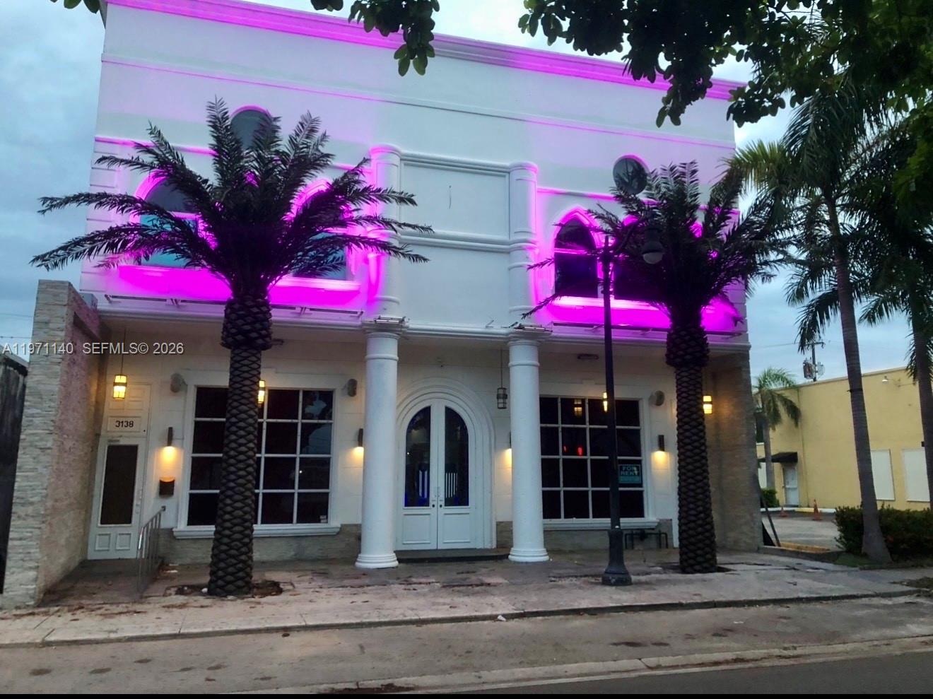 A two-story white building features arched windows with bright pink lighting and two palm trees — 3138 Coral Way, Miami FL 33145, MIAMI, FL