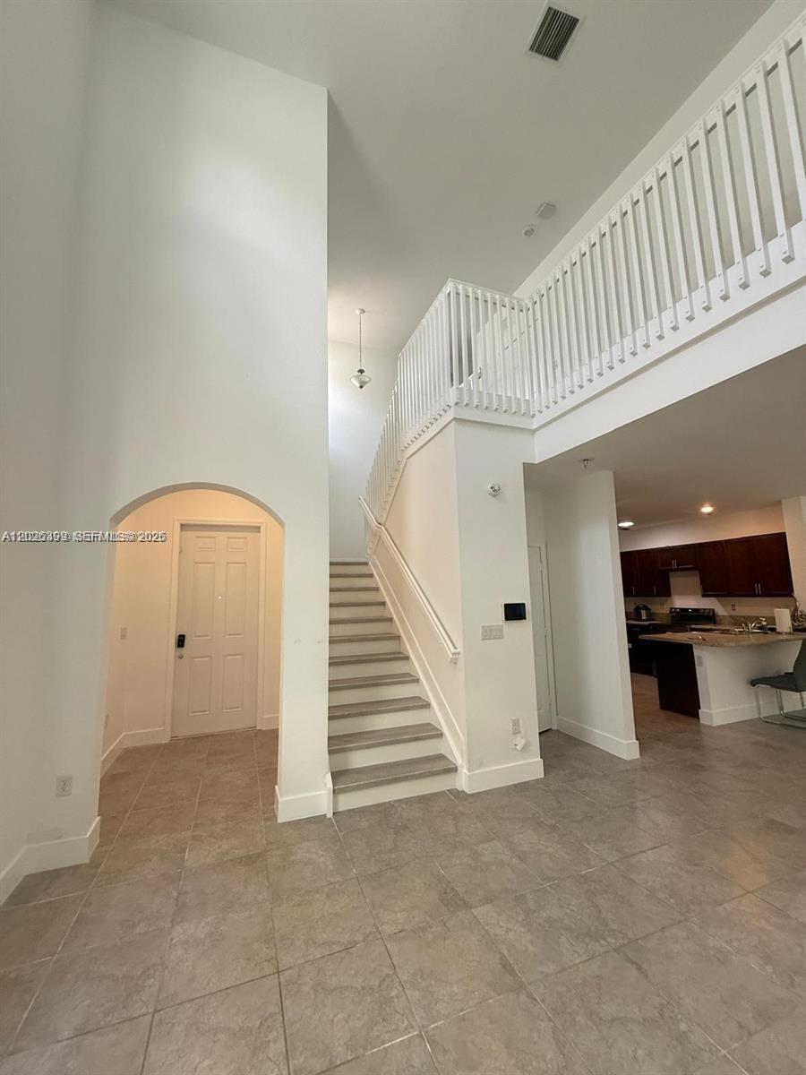 A two-story foyer features a staircase with white railings, tile flooring, and high ceilings — 156 NE 24th Ave, Homestead FL 33033, HOMESTEAD, FL