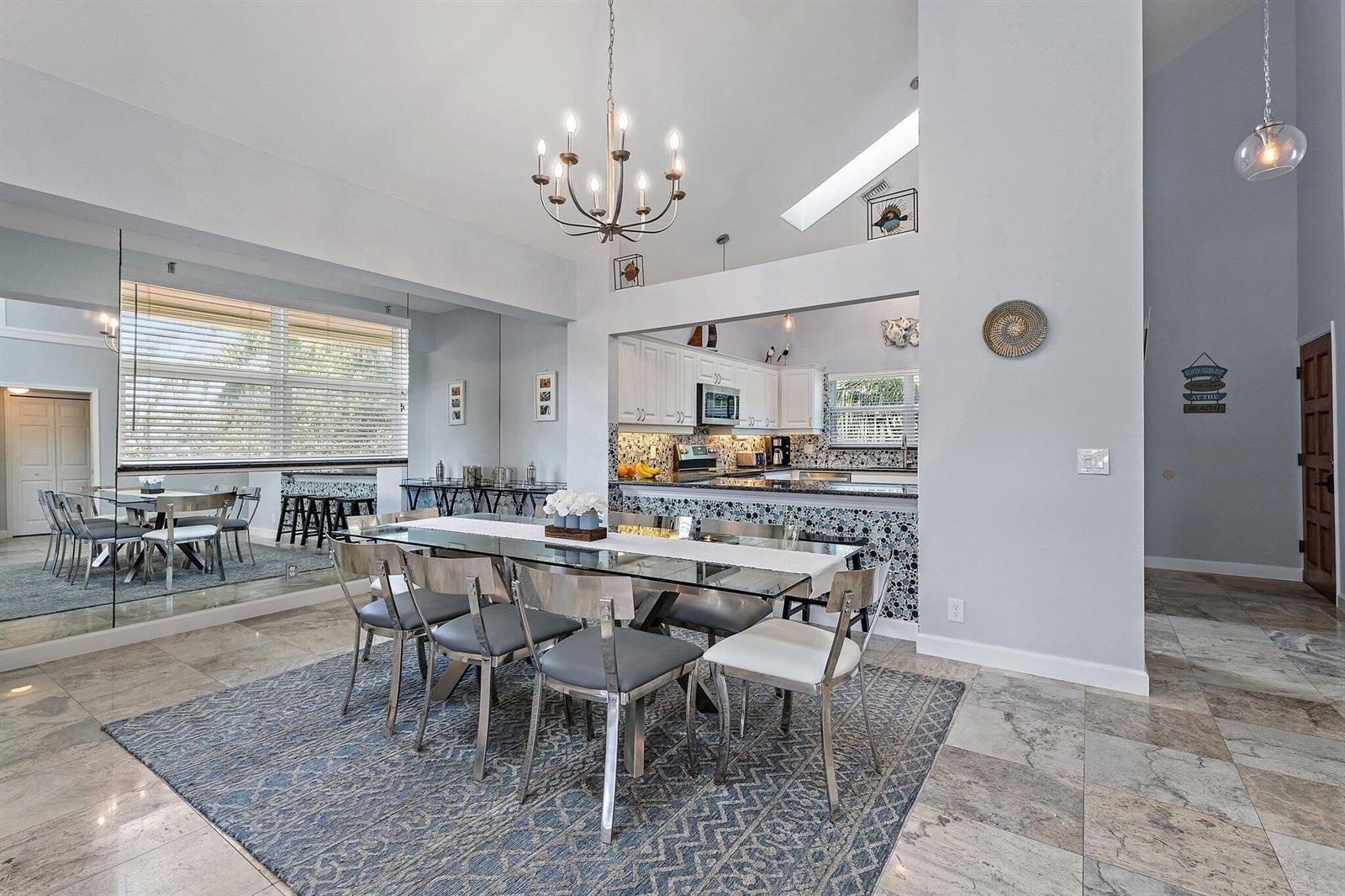 A dining area with a glass table and chairs sits before an open-concept kitchen — 4161 S. Us Highway 1 # G3, Jupiter FL 33477, JUPITER, FL