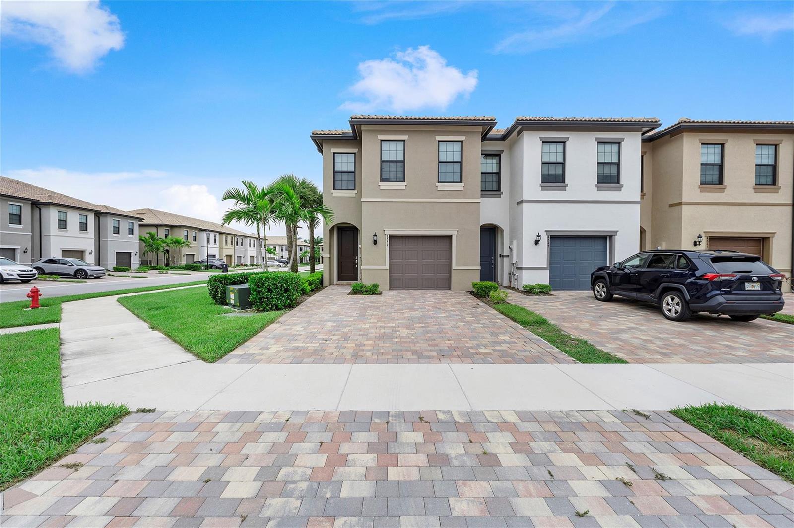 A two-story townhouse with a paved driveway, a one-car garage, and a tan exterior — 4851 Indio Trail, Lake Worth FL 33467, LAKE WORTH, FL