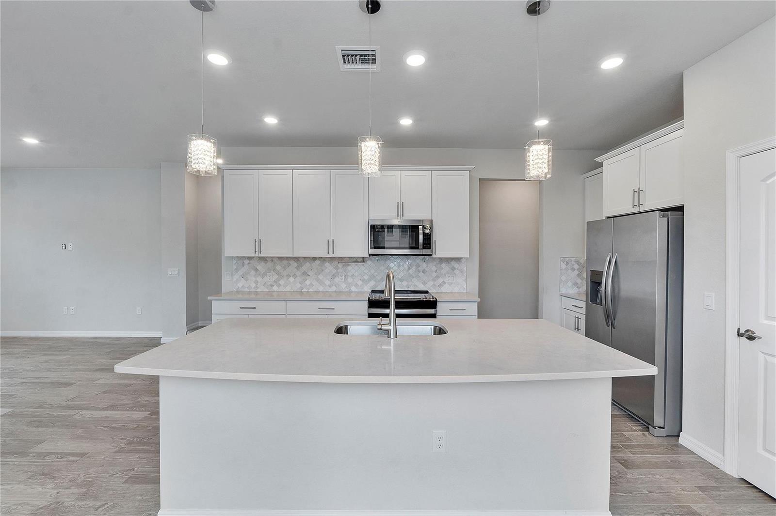 A kitchen features white cabinets, stainless steel appliances, a large island, and light-colored countertops — 4851 Indio Trail, Lake Worth FL 33467, LAKE WORTH, FL