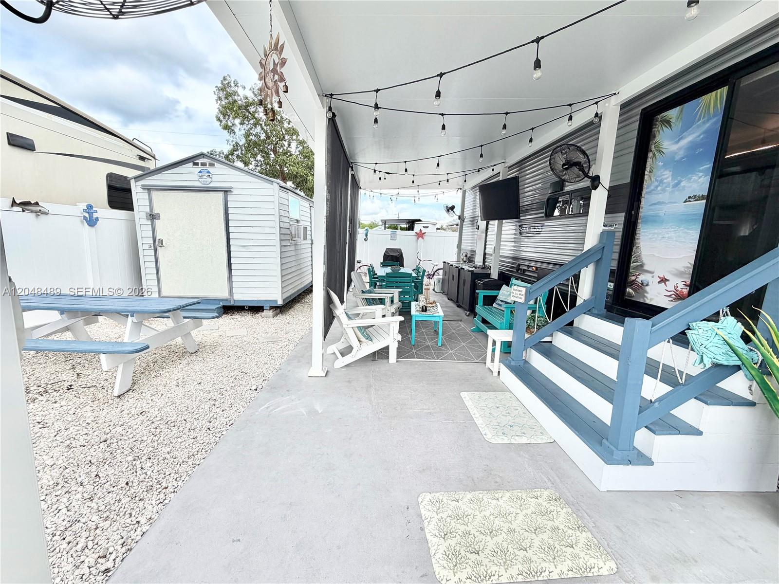 A covered patio features a picnic table, outdoor seating, and a storage shed on gravel — 325 Calusa St #425, Key Largo FL 33037, KEY LARGO, FL