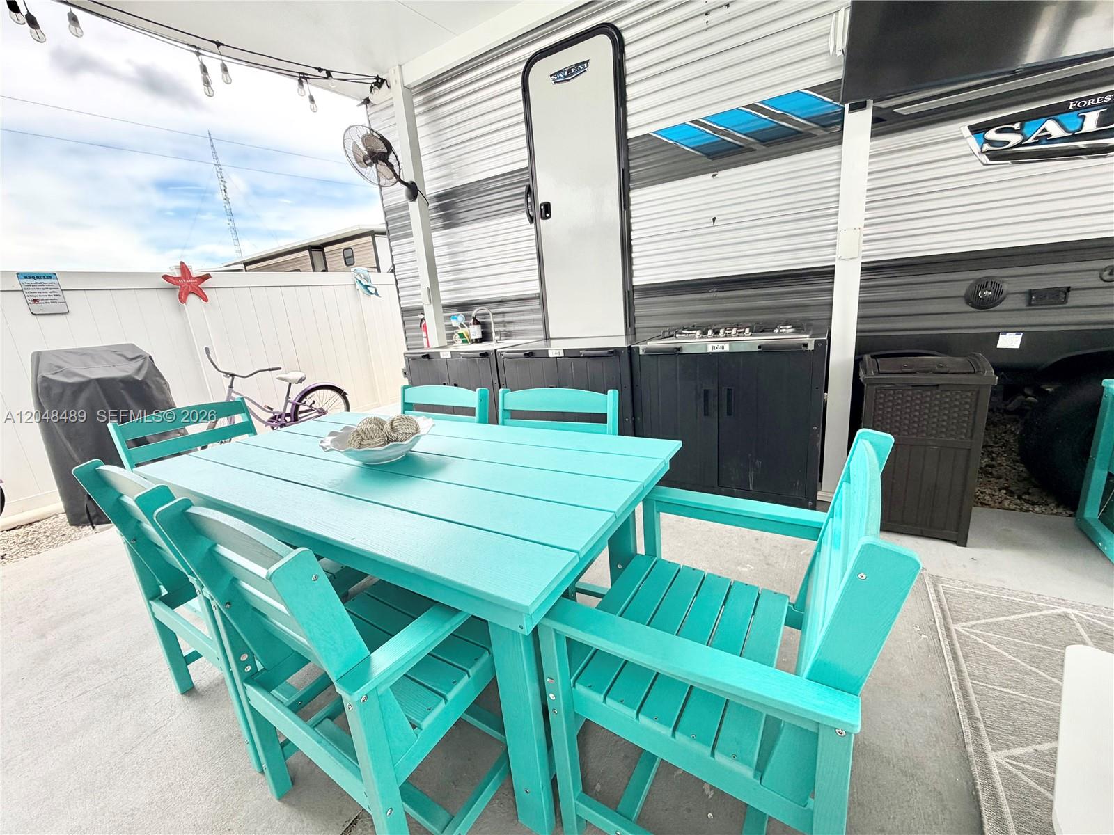 A turquoise dining set sits on a patio next to a camper and outdoor kitchen — 325 Calusa St #425, Key Largo FL 33037, KEY LARGO, FL