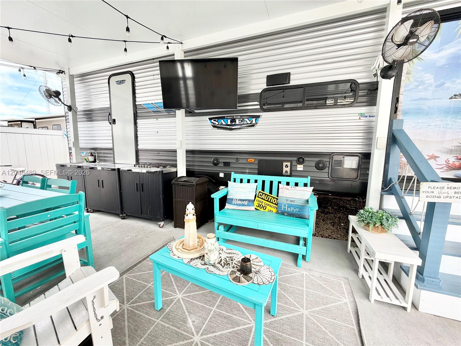 An outdoor patio space features a travel trailer, turquoise furniture, and a television — 325 Calusa St #425, Key Largo FL 33037, KEY LARGO, FL