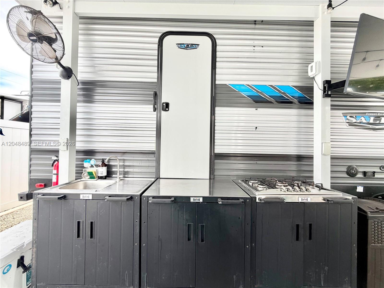 An outdoor kitchen with a sink and stove is installed against the side of a trailer — 325 Calusa St #425, Key Largo FL 33037, KEY LARGO, FL