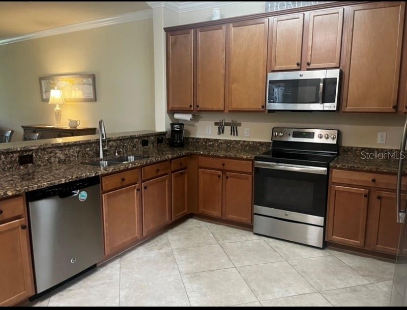 A kitchen features wood cabinets, granite countertops, stainless steel appliances, and light tile flooring — 6760 WILLOWSHIRE WAY, BRADENTON, FL